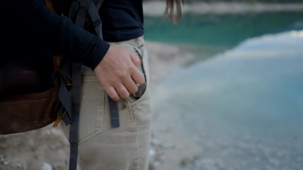 Unrecognizable Girl Takes Compass Out of Pocket and Opens It By Lake alt