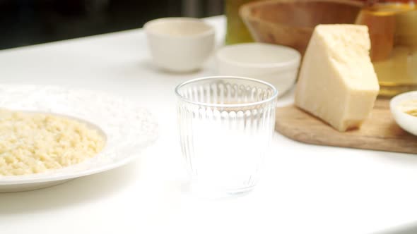 Crop chef pouring white wine for risotto in glass alt