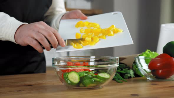 Hands chef throws knife chopped bell pepper cutting board salad bowl in kitchen alt
