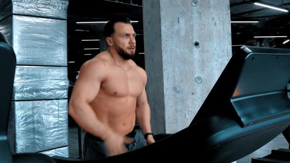 An Attractive Man Bodybuilder Running on the Treadmill and Changing Changes Modes alt