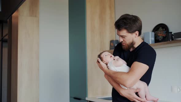 Love and Sincere Facial Emotions of Handsome Father While He Rocking and Calming Little Infant alt