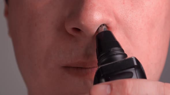 Man Removes Hair From the Nose with a Trimmer. Close-up