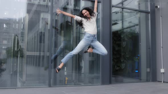Woman with Long Curly Hair Dynamic Jumping Into Air Laughing Smiling Celebrating Victory Winning alt