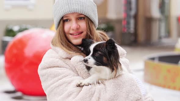 Beautiful Girl with Dog Papillon in Her Arms on Winter Christmas Streets alt