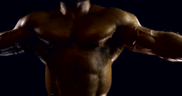 Close-up Portrait of a Male Naked Body of a Bodybuilder, He Is in the Studio on a Black Background alt