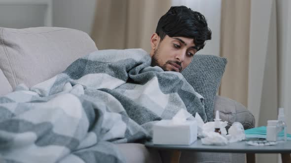 Indian Bearded Sad Exhausted Man Lying on Home Couch Ill Covered Blanket Suffering From Fever alt