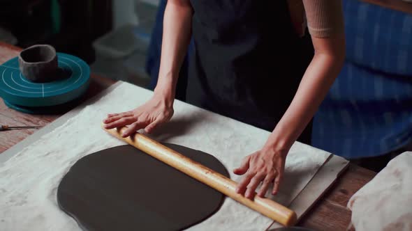 A female ceramicist is creating a new pottery in the workshop. Asian woman is enjoying pottery work. alt