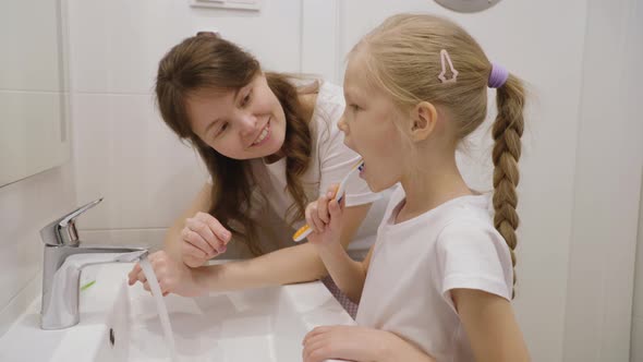 Mother and Daughters Brushing Teeth Together