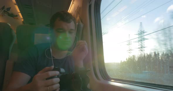 Man traveler shooting video through train window alt