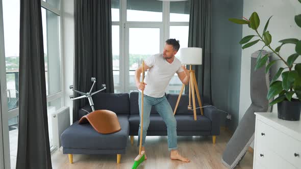 Man Cleaning the House and Having Fun Dancing and Singing with a Broom alt