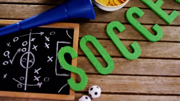 Bowl of snacks, football, horn and slate on wooden table 4k alt