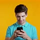 Handsome Man Texting in Messenger. Guy Sighs. Yellow Studio Background. Technology, Smartphone - VideoHive Item for Sale