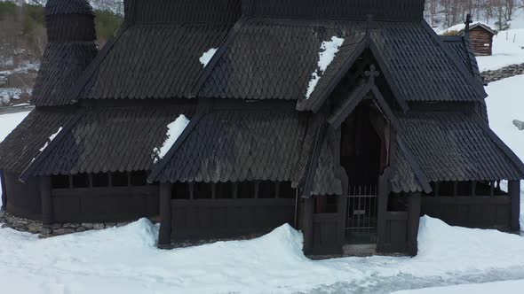 Borgund Stave church Norway - Winter low altitude aerial rotating slowly around entrance alt