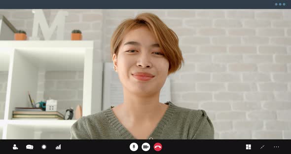 Happy Asian women making online video call at home smiling and listening to interlocutor