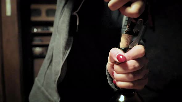 Woman with red nail polish pulling cork out of wine bottle. Slow mo close up on hands. No face. alt