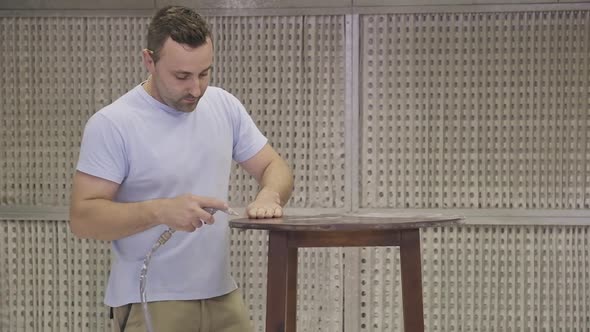 Workman using airbrush for applying flame retardant to wood detail ensuring fire protection alt