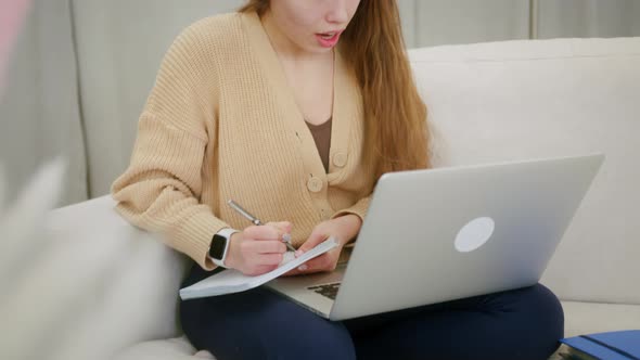 Smiling young woman sit on couch at home use laptop, talk by webcam video conference. alt