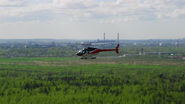 Helicopter Blue White Red Colors Flies Against a Background of Blue Sky and Green Fields and