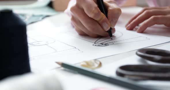 The designer draws a sketch of a woman's bag on paper at the workplace alt
