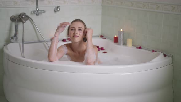 Wide Shot of Confident Relaxed Caucasian Slim Young Woman Posing in Bathtub at Home Indoors alt