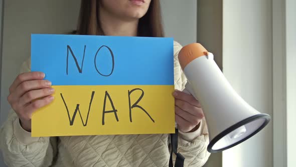 Young Woman with a Poster and a Megaphone in Her Hands Calls for an End to the War in Ukraine
