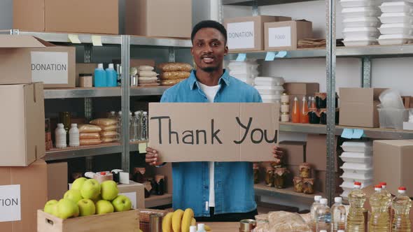 African American Guy Holding Banner with Text Donation at Food Bank alt