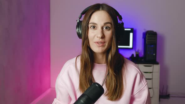 Woman in Headphones with Mic Broadcasting at Modern Studio in Neon Light alt