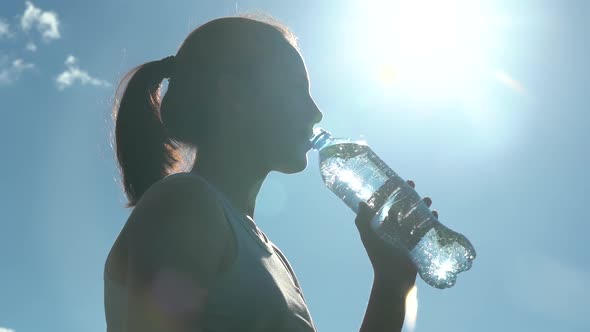 A Girl Quenches Her Thirst Against a Backdrop of Sultry Clear Skies