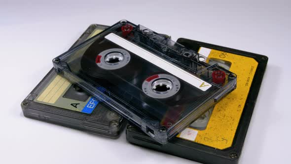 Three Vintage Audio Cassettes Rotate on White Background alt