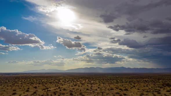 Heavy storm clouds obscuring sun over Mojave Desert landscape, Aerial Hyperlapse alt
