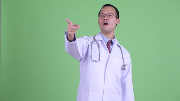 Happy Asian Man Doctor with Eyeglasses Pointing Finger and Directing alt