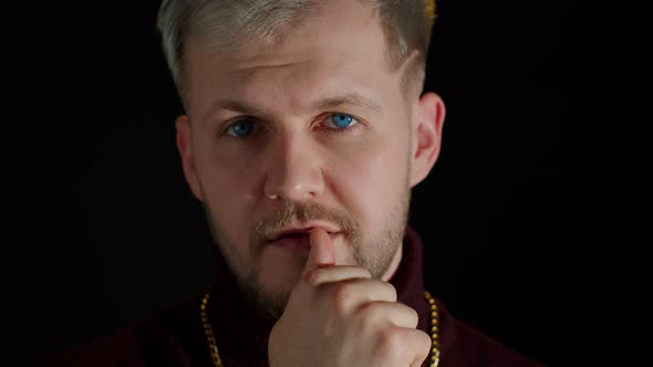 Confident Bearded Man in Stylish Clothing Sensually Touching Lips with Finger on Black Background alt