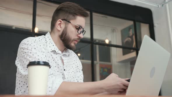 Man in Office Talking at Phone and Type at Laptop