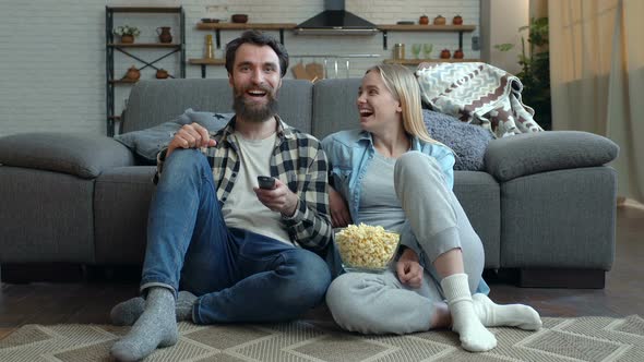 Laughing, happy couple watching tv