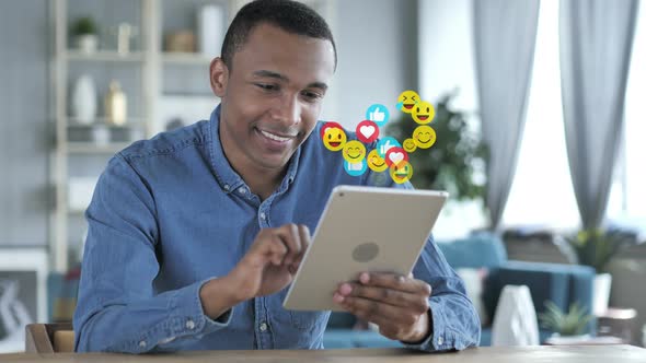 Happy African Man Using Tablet, Emojis, Smileys and Likes alt