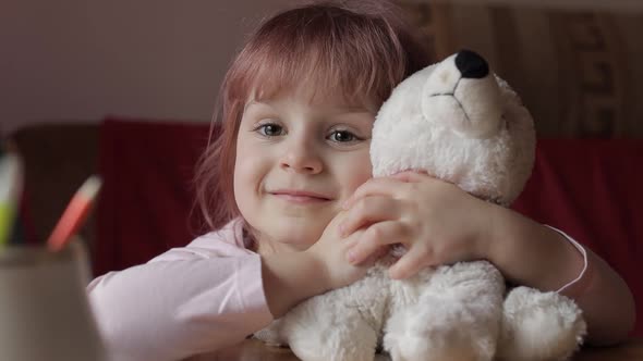 Cute Small Child Girl Sitting at Home Playing and Hugging Her Teddy Bear Toy alt