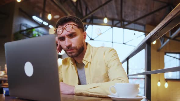 Exhausted Millennial Male Hold Head with Hand Sitting at Office Table Falling Asleep Tired Man Fall alt