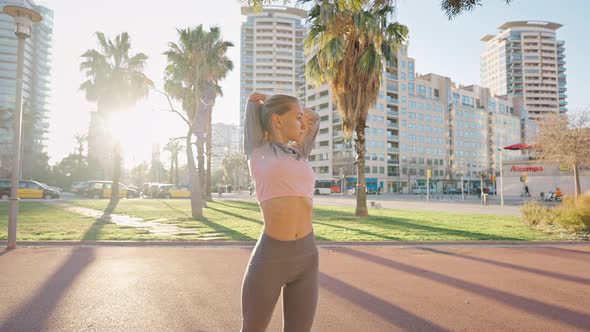 Young Woman in Sportsuit Stand on Street Do Stretching Exercises alt