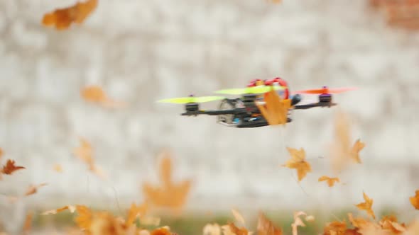 The Drone Flies Quickly and Low Above the Ground, Lifting Leaves From the Ground in the Wind alt