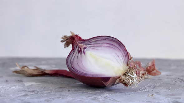 Half of fresh tropea red onions turning on a white table close up alt
