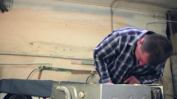 The Man Unscrews the Screws on the Top of the Washing Machine alt