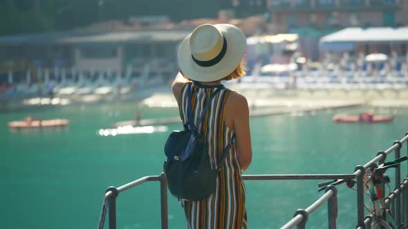 A woman looks at a Mediterranean Sea beach club in a luxury resort town in Italy, Europe alt
