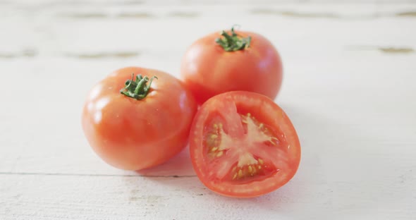 Video of halved and whole fresh red tomatoes on white rustic background alt