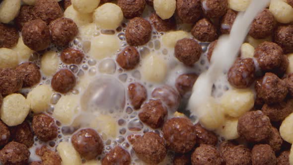 Milk Pouring Into a Bowl with Chocolate Balls Cereals for Breakfast