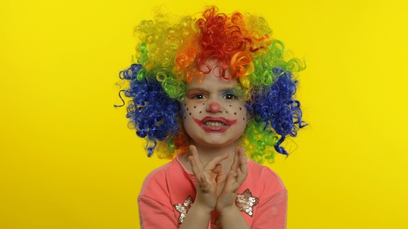 Little Child Girl Clown in Rainbow Wig Making Silly Faces, Having Fun, Laughing, Dancing. Halloween alt
