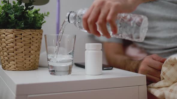 Asian man water pouring into the glass while in the bedroom at home.