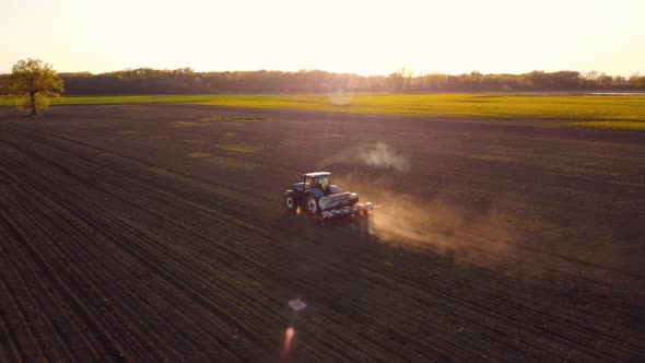 Tractor Working in Field at Sunset alt