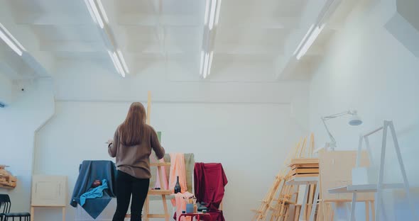 Young and Pretty Girl Draws at the Easel From Life alt
