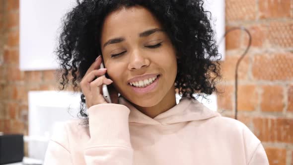 AfroAmerican Woman at Work Talking on Smartphone with Customer alt