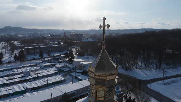 Aerial shot: flying around the goldened church dome with a cross.